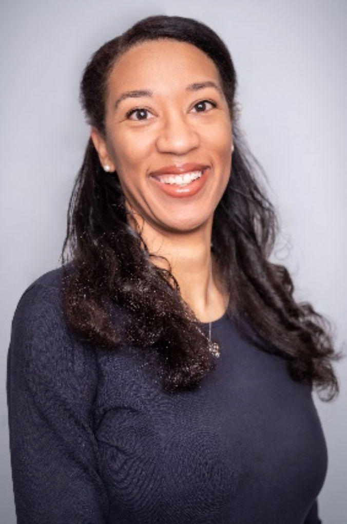 Smiling Black woman with long hair, wearing a dark pullover and silver heart necklace