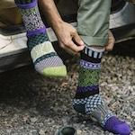 Model wearing crew socks in multiple shades of green & a little purple with a knit pattern
