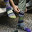 Thumbnail: Model wearing crew socks in multiple shades of green & a little purple with a knit pattern