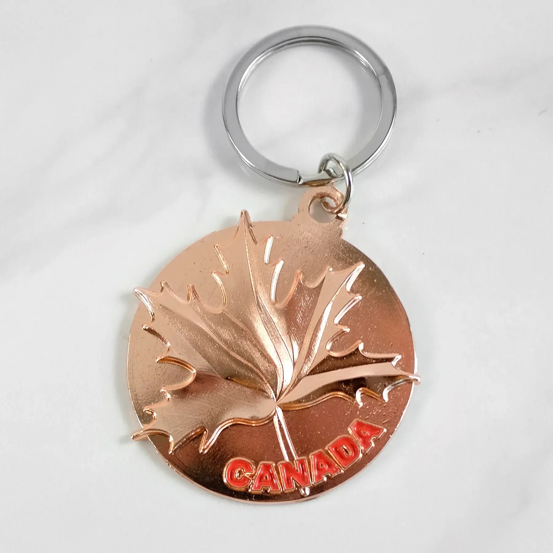 Round maple leaf embossed on a circular keychain at Tickled Pink Ottawa