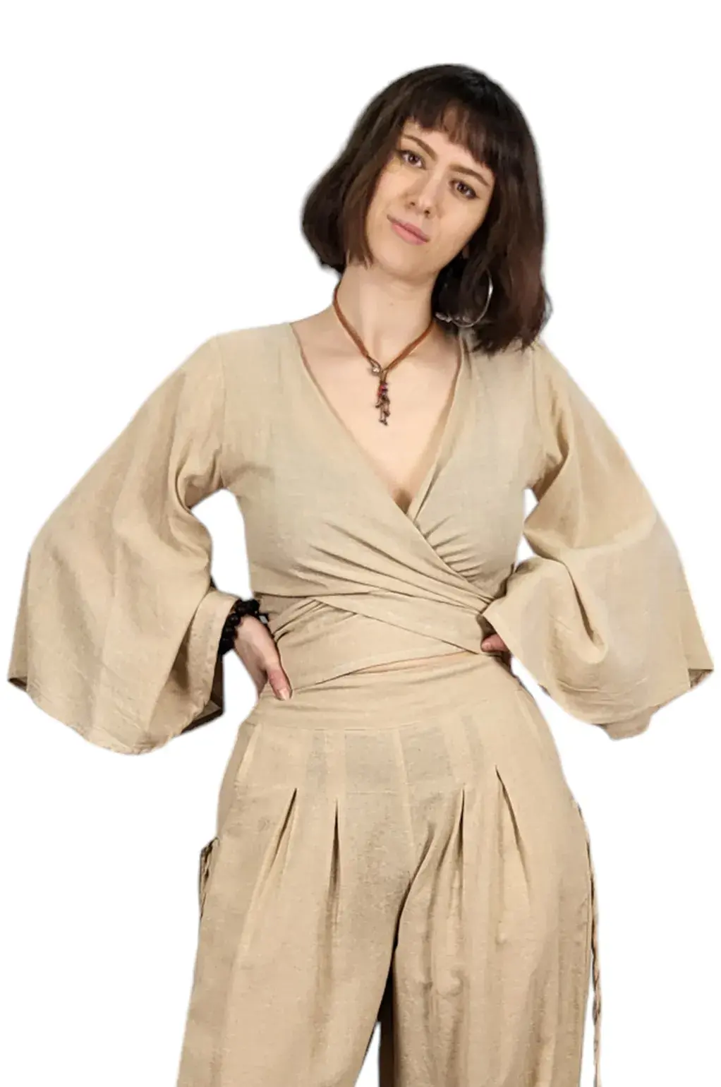 Front view of model wearing waist length solid beige wrap-around top with big bell sleeves