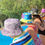 Thumbnail: Girls seen from back sitting on edge of pool wearing colorful bucket hats