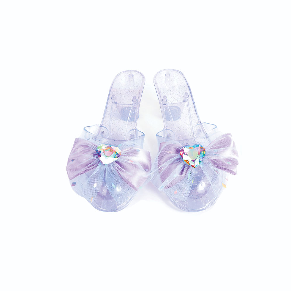 A pair of lilac glitter dress-up shoes featuring large purple tulle bows and heart-shaped iridescent gems at Tickled Pink.