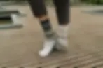 Standing model wearing black, tan & gray mismatched crew socks in knit pattern