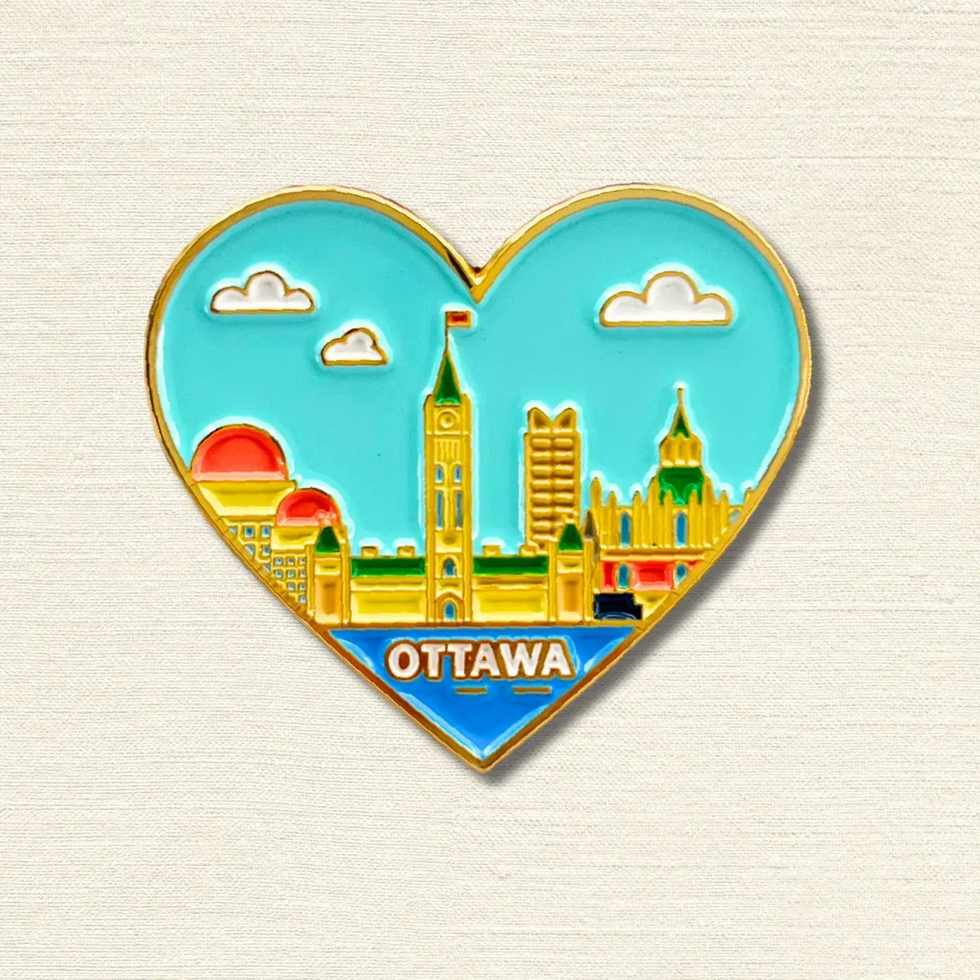 Heart shaped enamel pin with scene of Canadian Parliament Buildings & blue sky