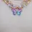 Thumbnail: Model wearing 2 beaded necklaces, each with opposing 1/2 butterfly pendant