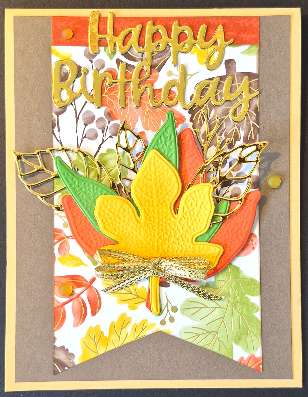 A handmade birthday card featuring a banner layout with textured maple leaves and metallic accents at Tickled Pink.