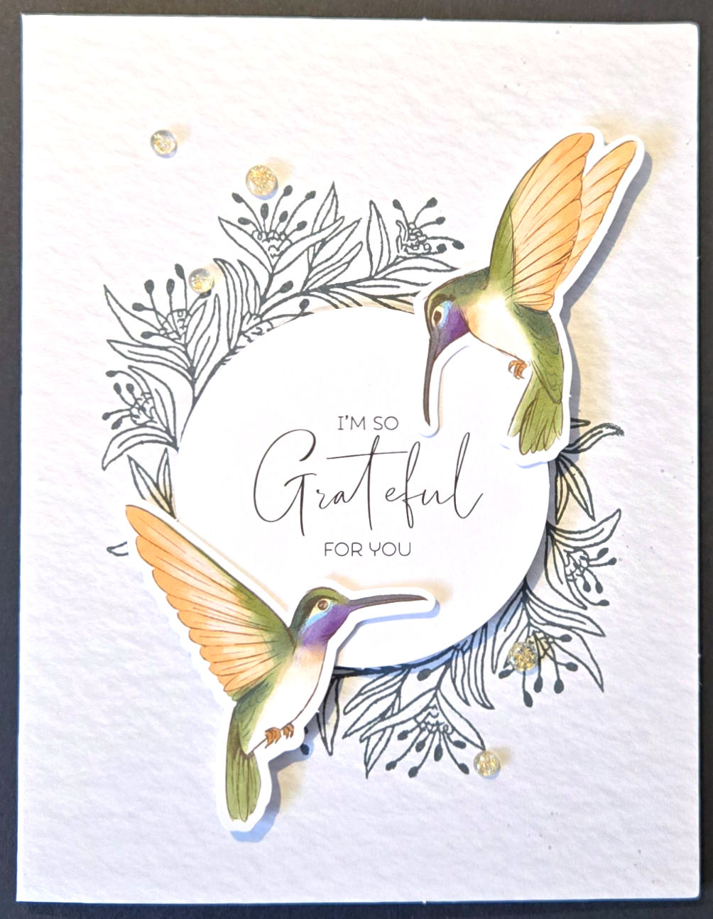 Textured off-white card with 2 hummingbirds around floral center, text , 'I'm so grateful for you'