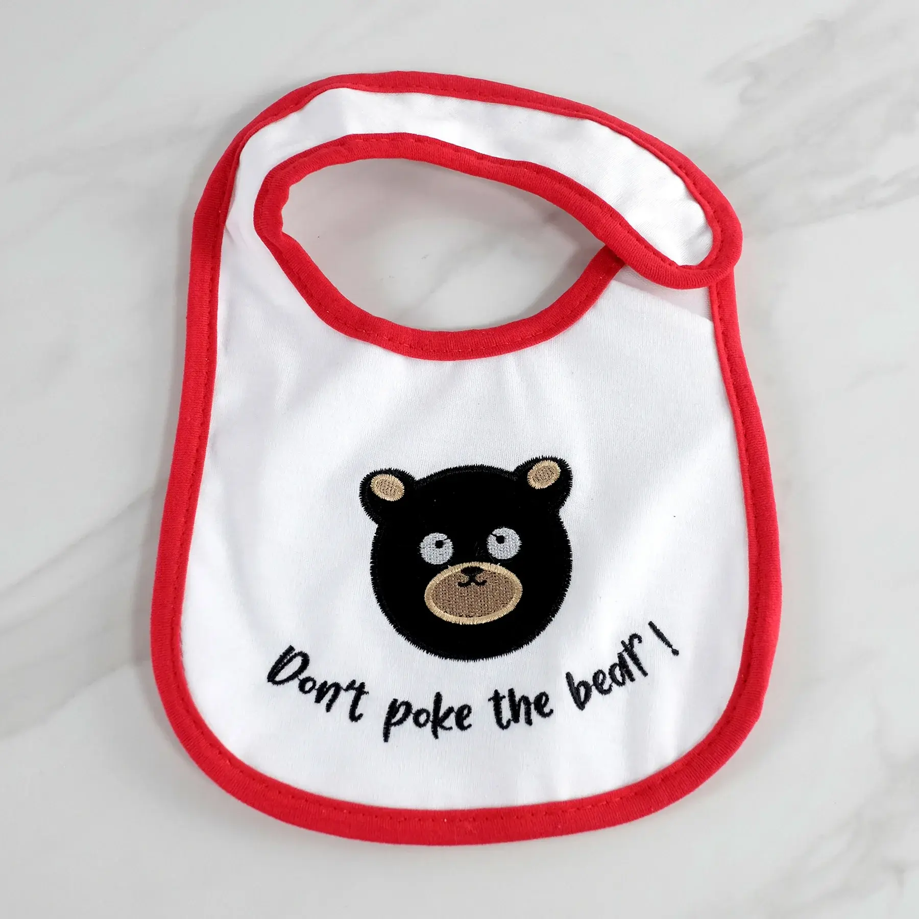 Tickled Pink's embroidered baby bib featuring a cute bear face and the text Don't poke the bear!