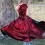 Thumbnail: Back view of child wearing shiny red metallic dragon cape with fierce eyes, horns & spiked tail