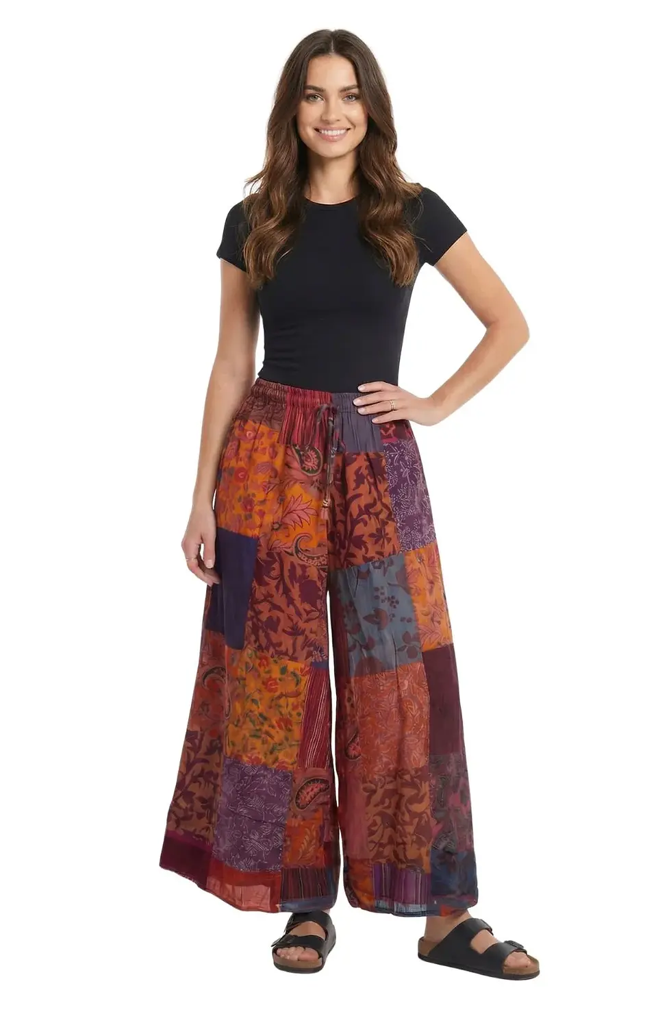 Model wearing elastic waist, wide leg multi colored patch pants in predominantly burgundy shades