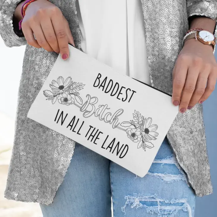 Person holding zipper pouch stamped with black & white Baddest Bitch in all the Land design