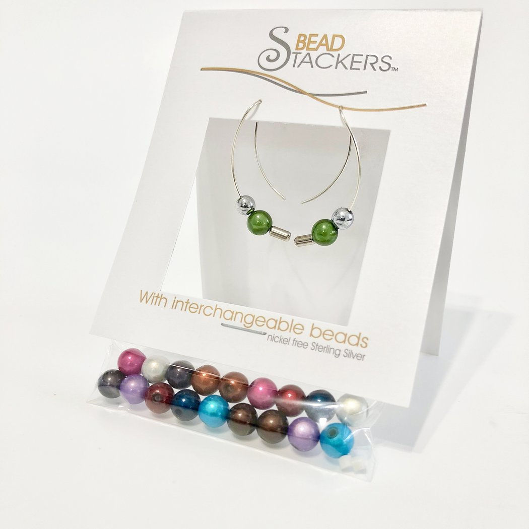 Package of interchangeable long curved silver earrings with green beads and bag of many colored beads