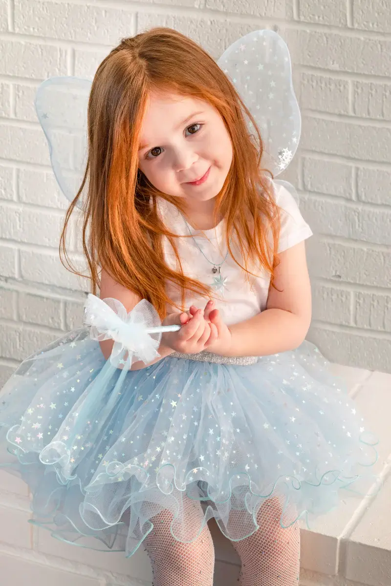 Front view of little girl wearing pale blue glittery tutu, wings & wand dress-up set