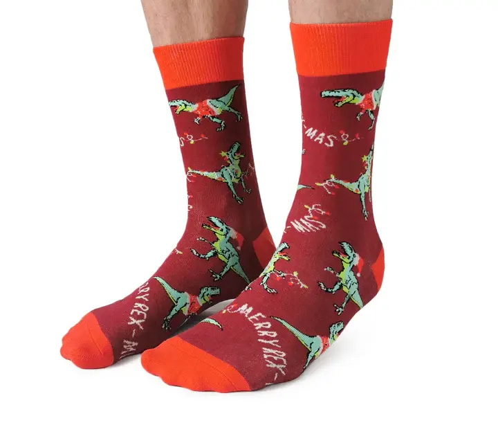 Angled front view of pair of red socks with festive green T-Rex print