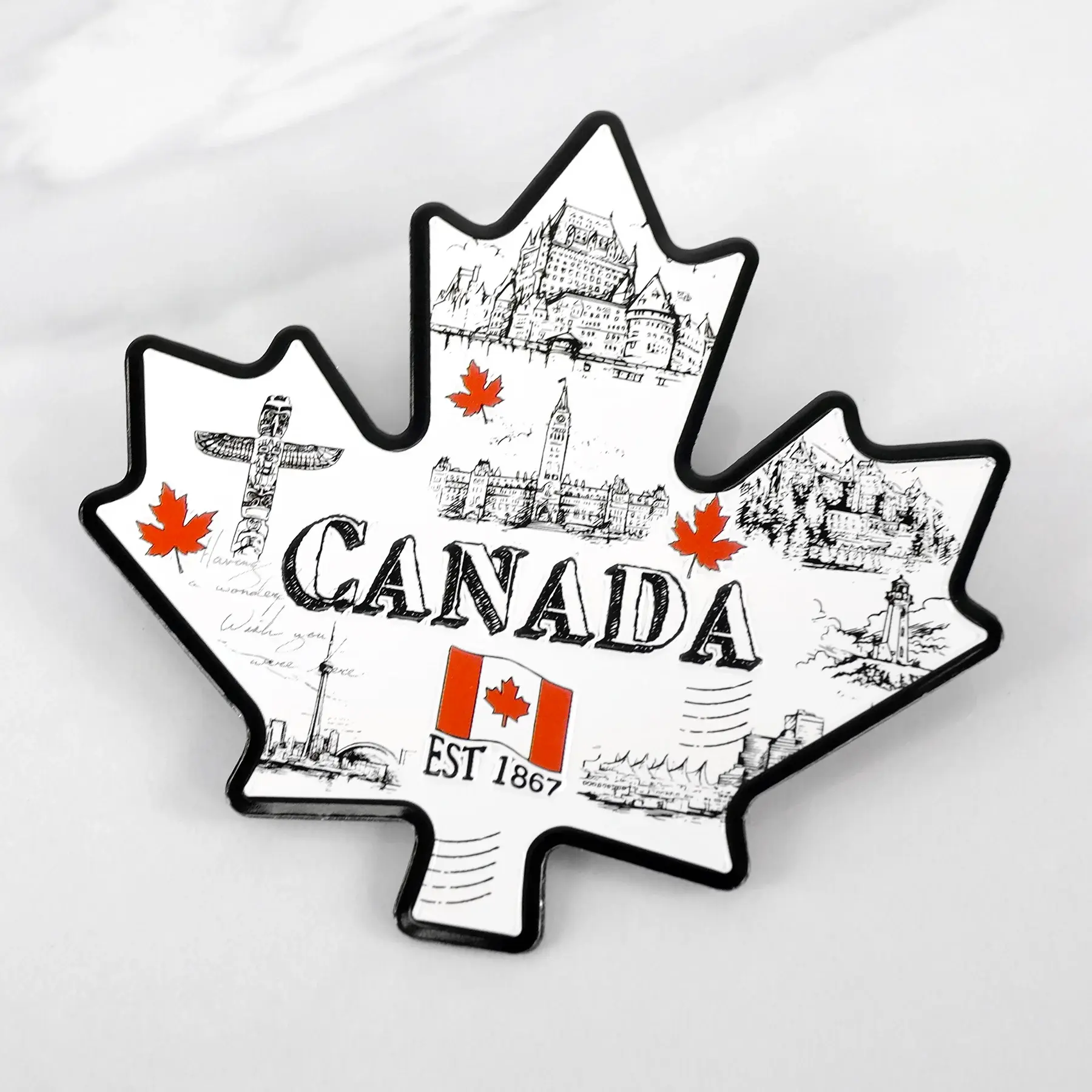 Black & white maple leaf shaped magnet with line drawings of Canadian icons, red maple leaves & Canadian flag