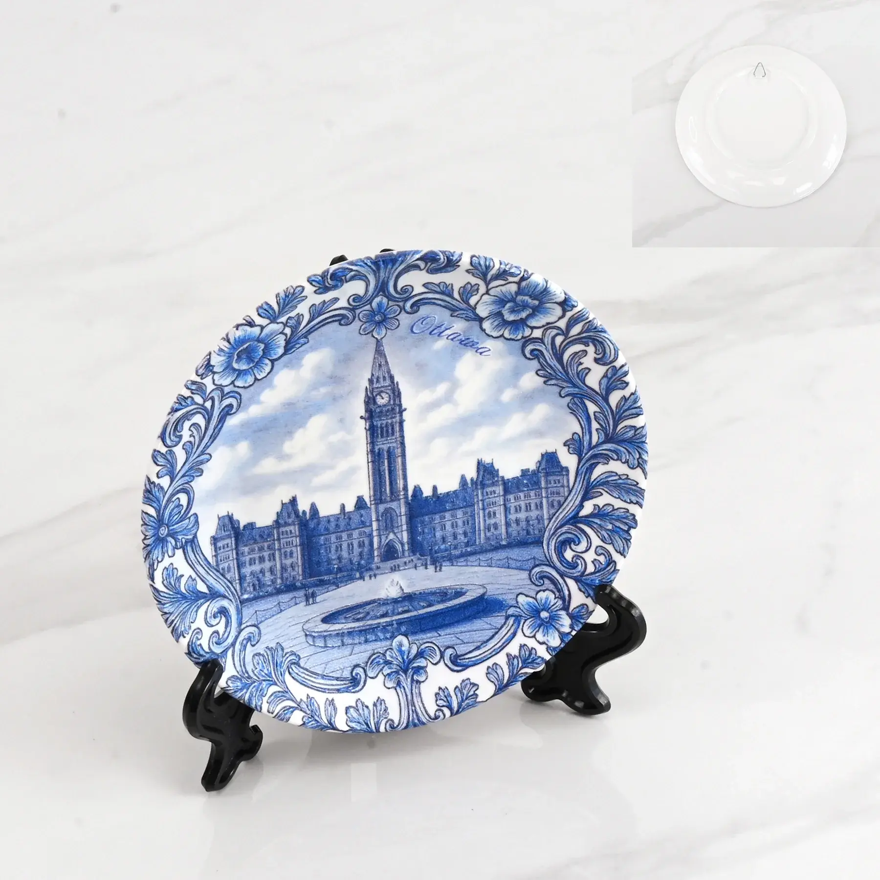 A blue and white ceramic decorative plate illustrated with Ottawa's Parliament Hill, shown on a display stand at Tickled Pink