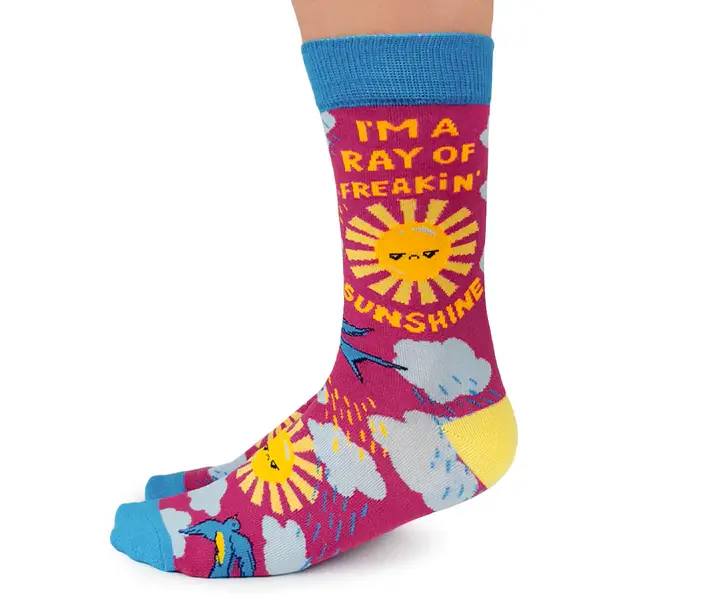 Side view of pair of red, yellow, white & blue socks with sunrays, clouds, text, I'm a freakin' ray of sunshine