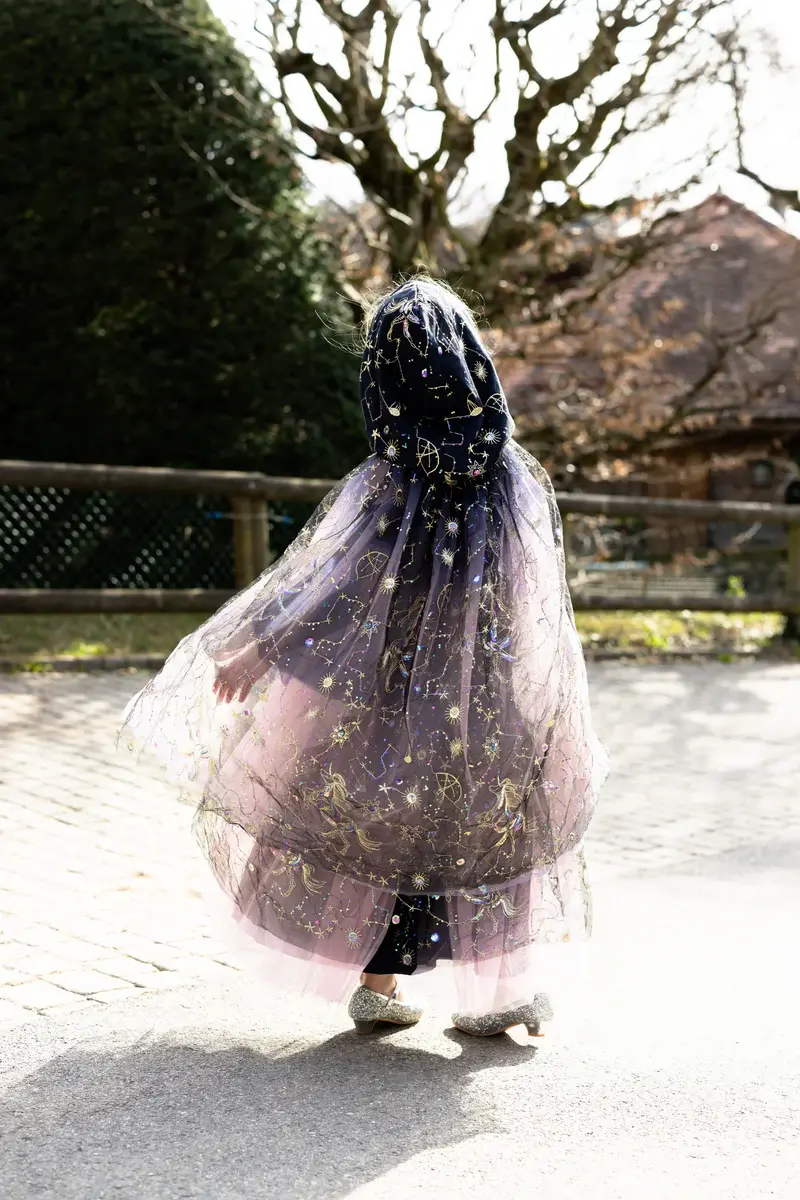 Back view of child wearing long purple cape with gold stars & constellations embroidered on tulle over-layer
