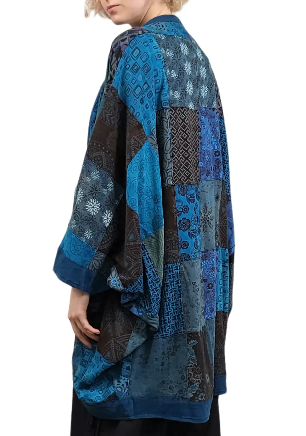 Thumbnail: Back view of model in cocoon shaped kimono style long jacket of blue patchwork with long sleeves
