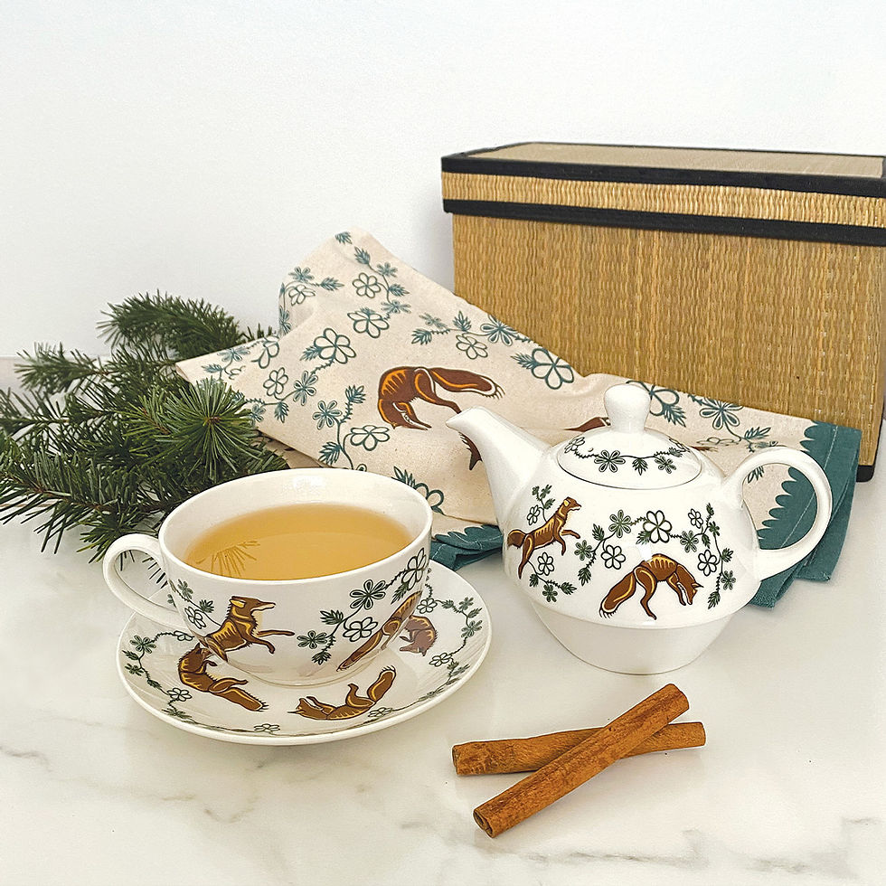 Brown & green teapot, cup & saucer set printed with artist Storm Angeconeb's 'Foxes' in use with tea