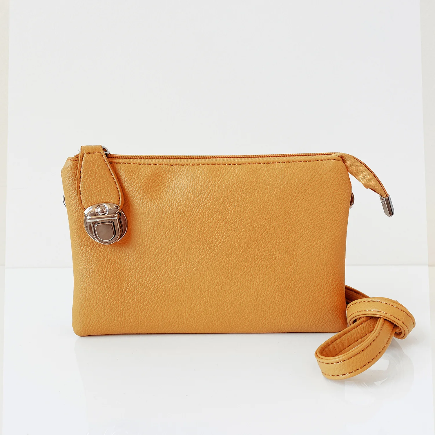 Yellow small rectangular purse with metal latch at left end & folded strap