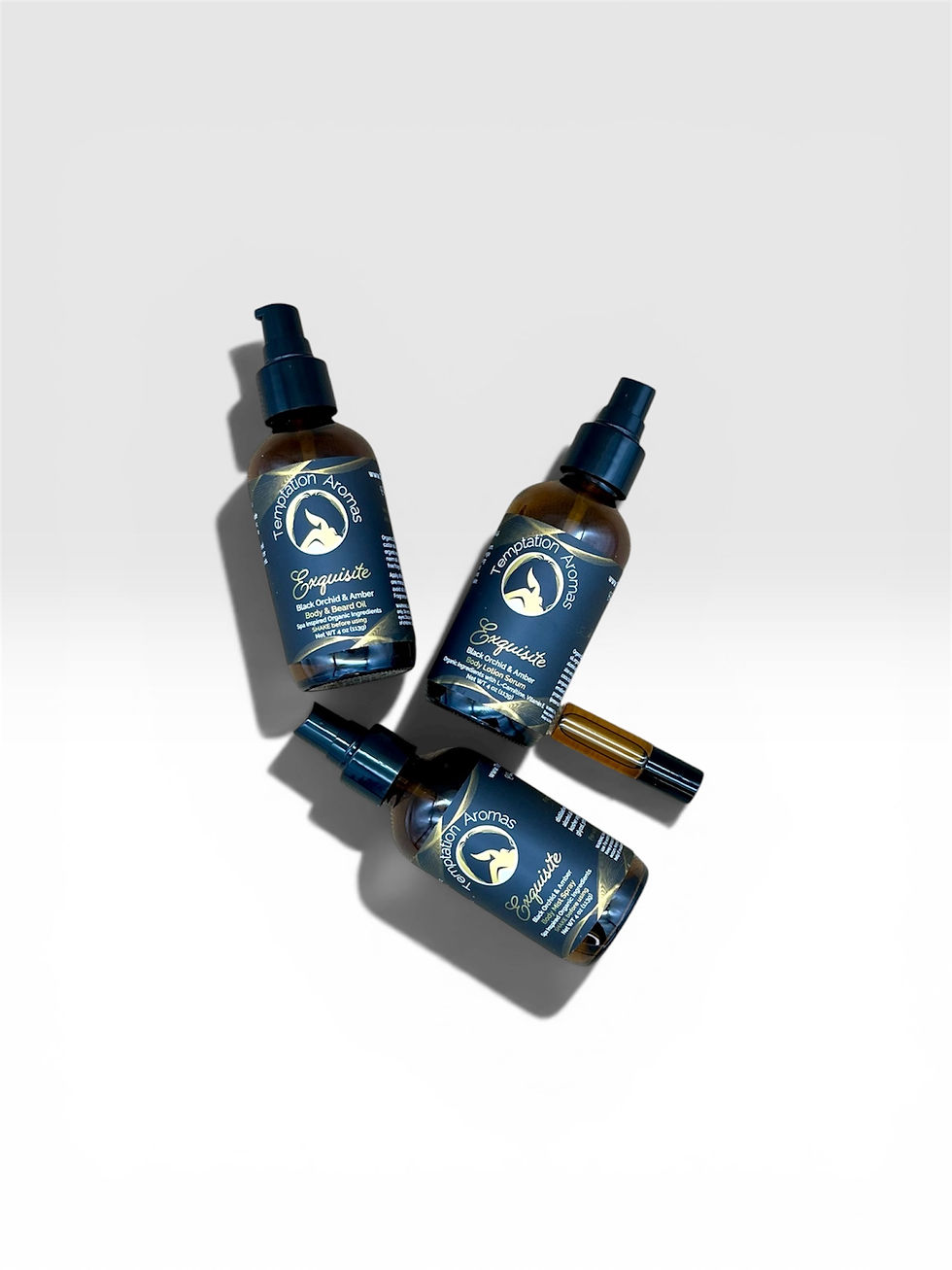 Thumbnail: Exquisite black orchid radiant gift set flat lay featuring three amber spray bottles and a perfume roll on