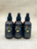 Mystique lavender 4oz bundle with two amber lotion bottles and one spray mist bottle on tan burlap background