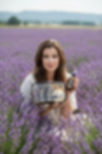 Woman holding a Mystique lavender travel gift set inside a vibrant purple lavender field.