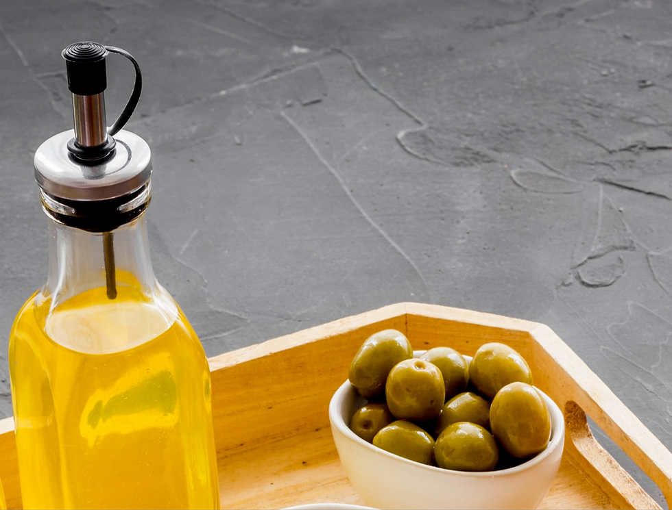 food grade organic extra virgin olive oil beside a bowl of green olives.