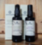 Two bottles of Annmarie skincare products on a wooden surface: Aloe Herb Cleanser and Neroli Toning Mist, with matching packaging.