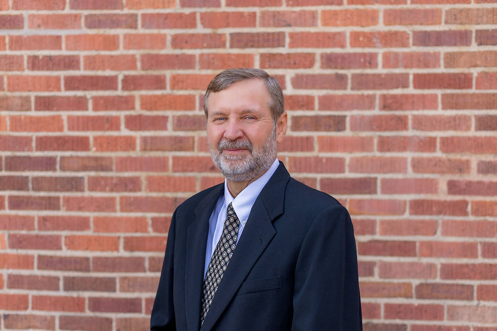 Professional headshot of Allan, financial forensic expert and consultant, smiling against a brick background