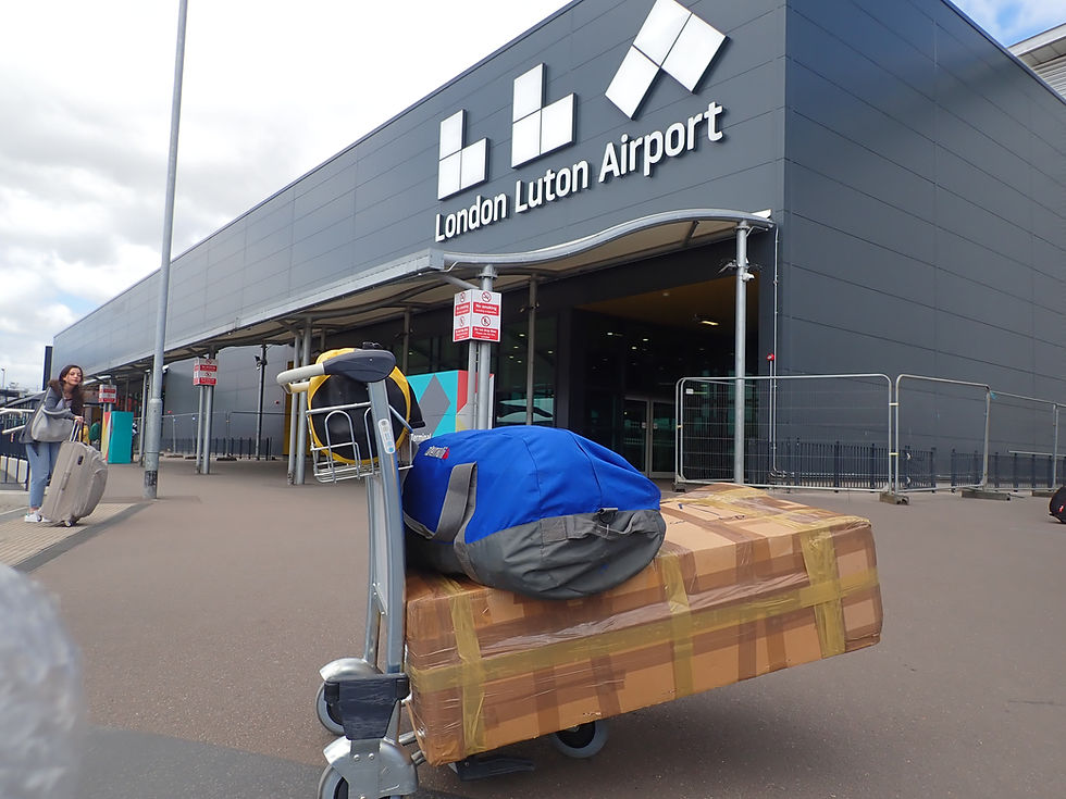 Luton airport terminal with a trolley in the foreground with my bike in a box and bikepacking gear