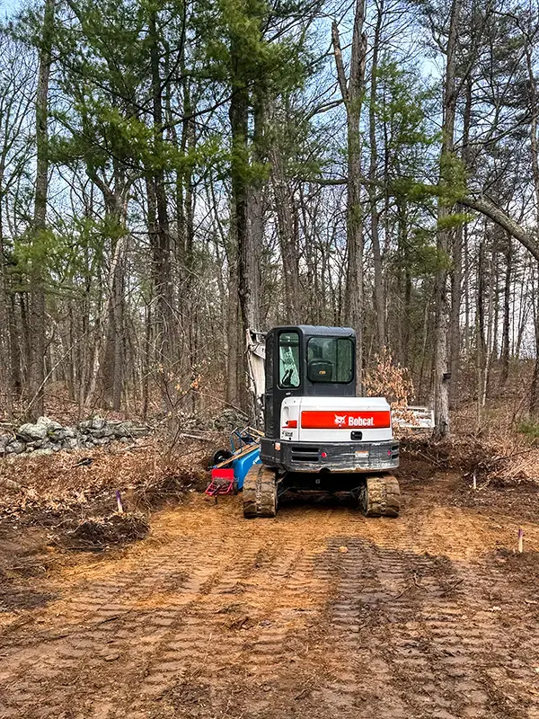Bobcat excavator on a dirt path in a wooded area