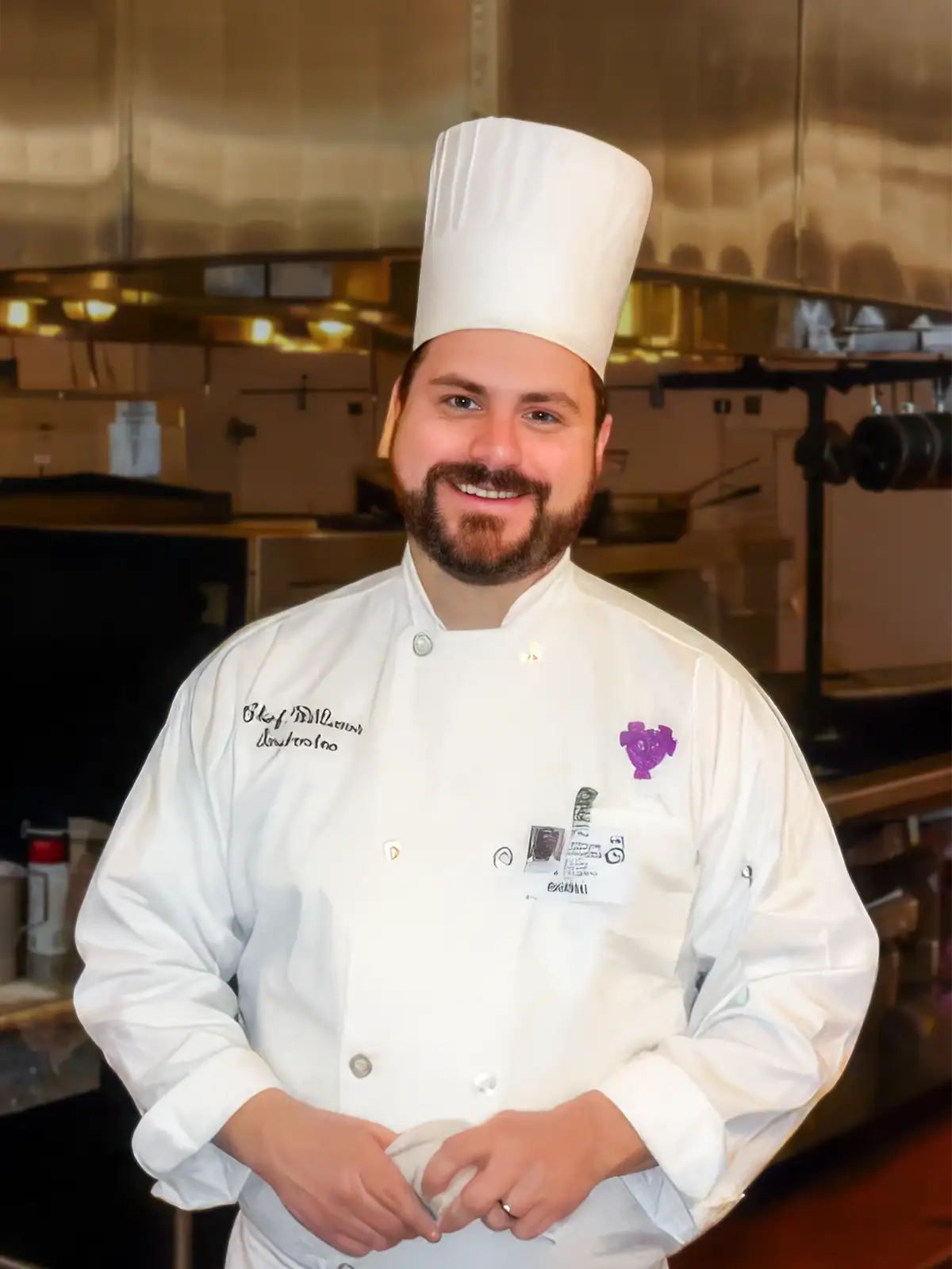 Chef Matt Williams in white chef's jacket and hat, standing in a kitchen