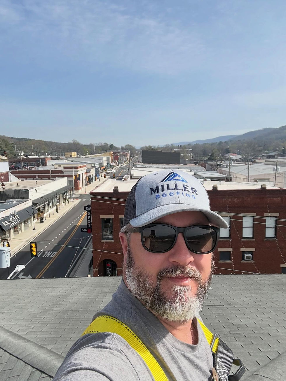 Josh Miller on the roof of a commercial building in alabama with Miller Roofing hat.