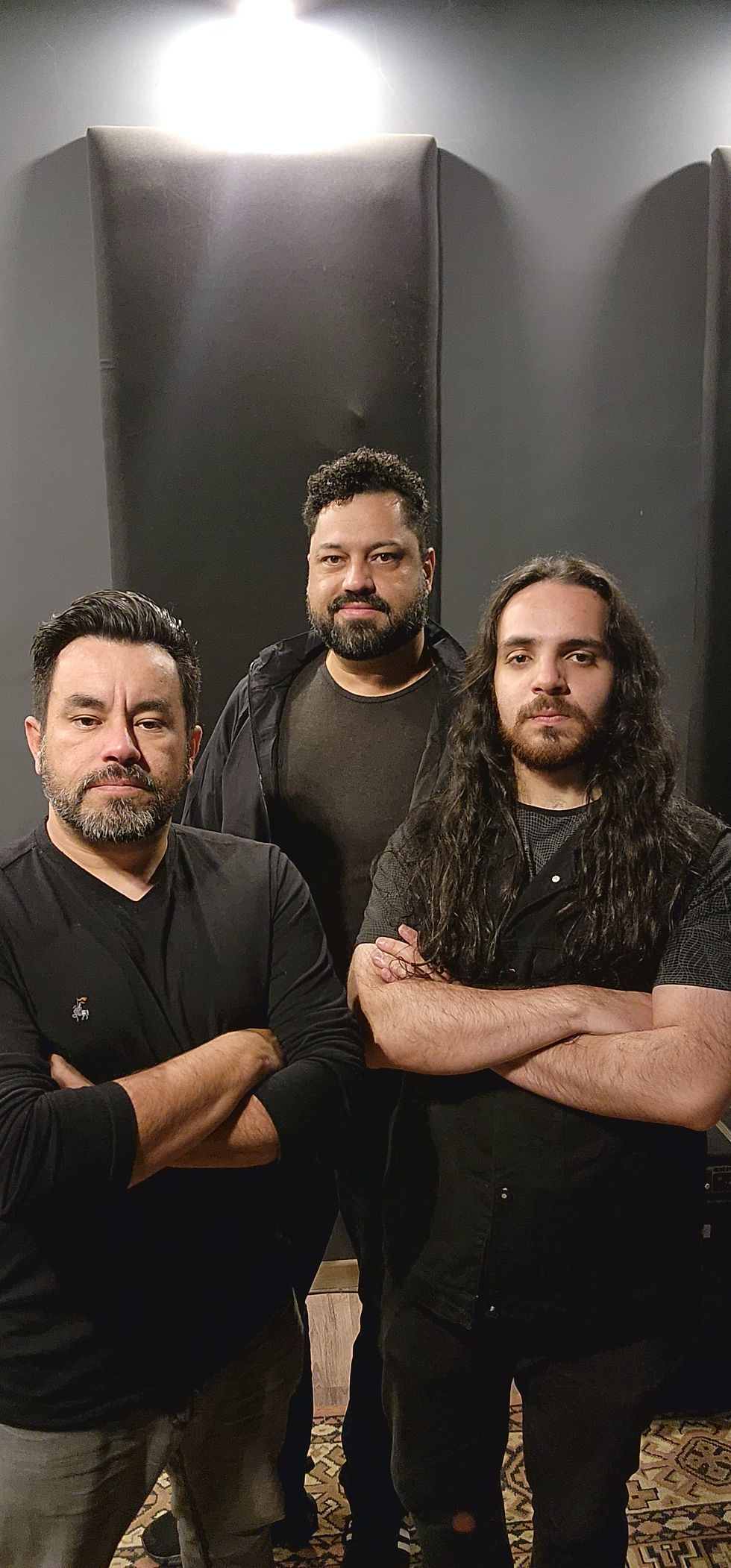 Três homens, banda musical, postura séria, estúdio musical