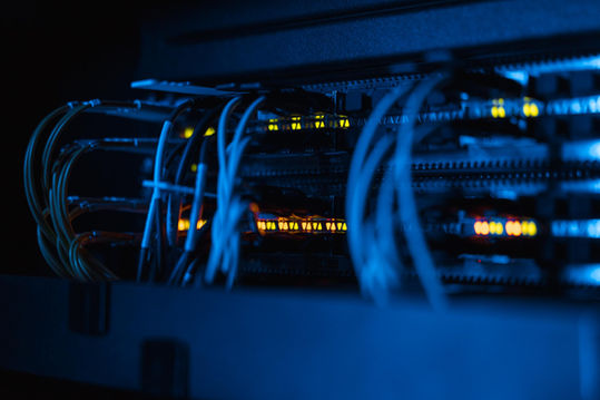 Detailansicht von Server-Racks, Netzwerkkabeln und aktiven gelb-orangen Statuslichtern.