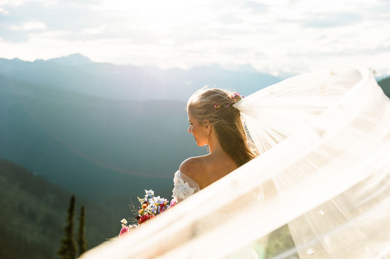 A bride stands overlooking the mountains during her Glacier National Park Elopement