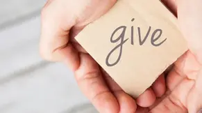 Hands holding a cardboard square with the word give