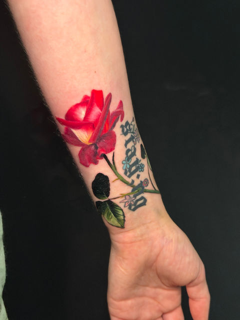 A wrist tattoo of a realistic red rose, detailed color realism by Ash & Ink Tattoo in Kelowna.