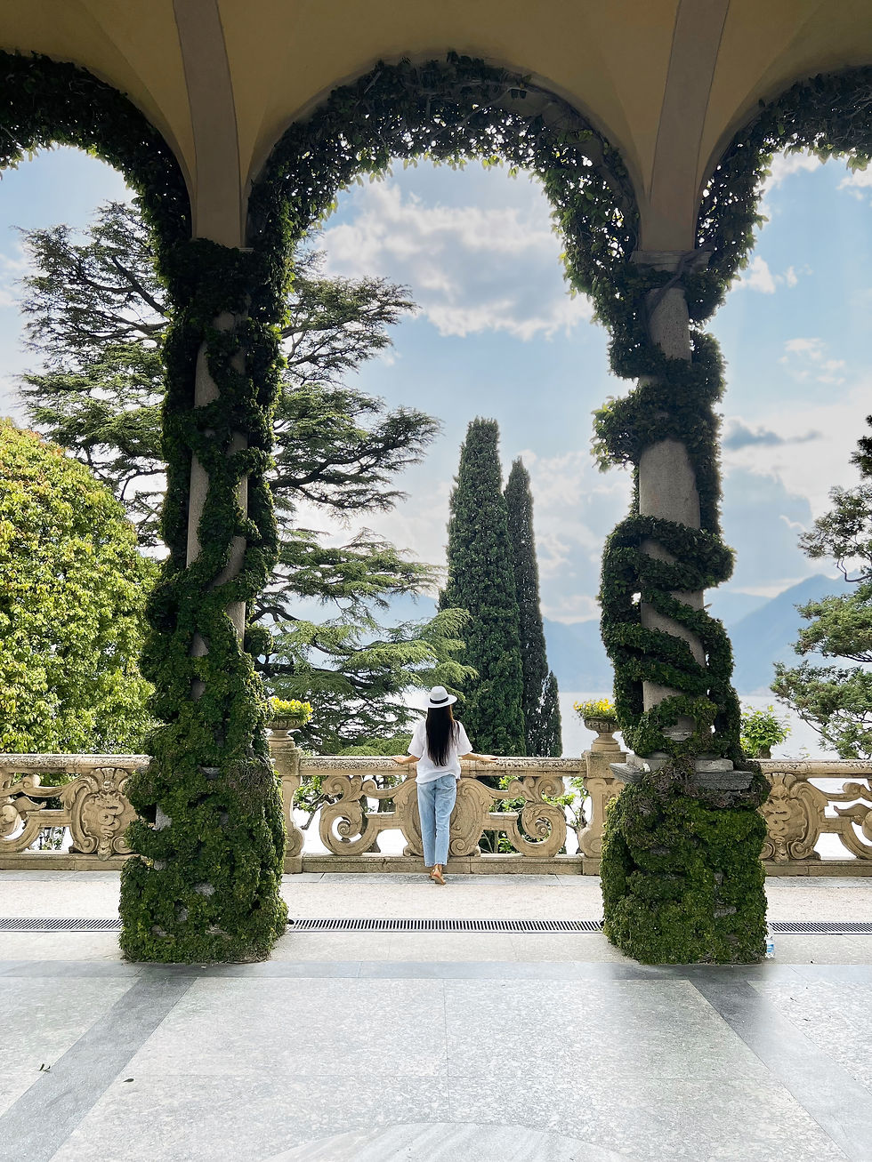 Elena is standing backwards facing the garden at the Villa del Balbianello in Lake Como, Italy