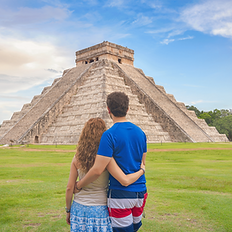 A couple facing the kukulkan temple at chichen itza