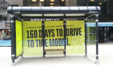 Bus Shelter with artwork that fills all 3 panels, stating "It would take a CTA bus approximately 160 days to drive to the moon."
