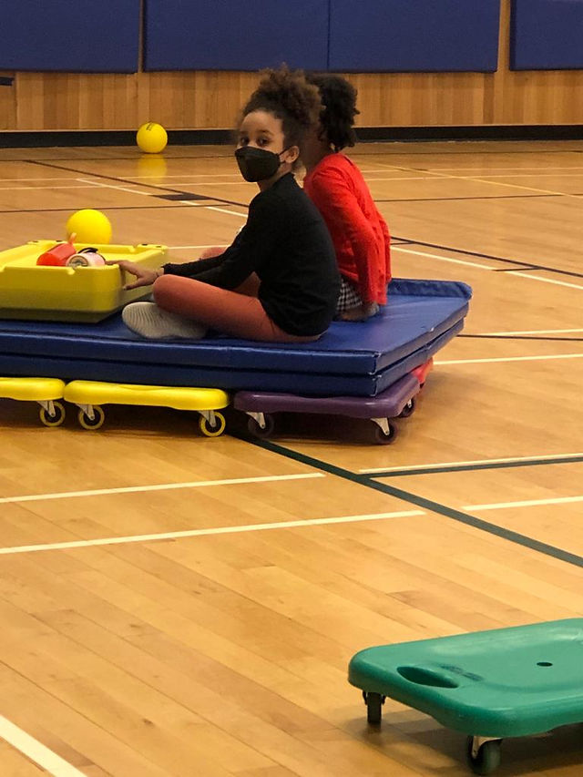 children playing on scooters in a gym