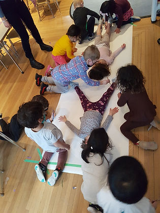children tracing another child's body onto paper