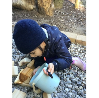 child pouring water on wood block