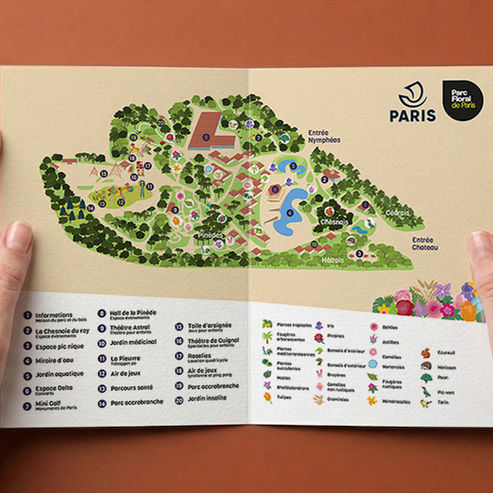 Mains tenant le dépliant ouvert de la carte touristique illustrée du Parc Floral de Paris