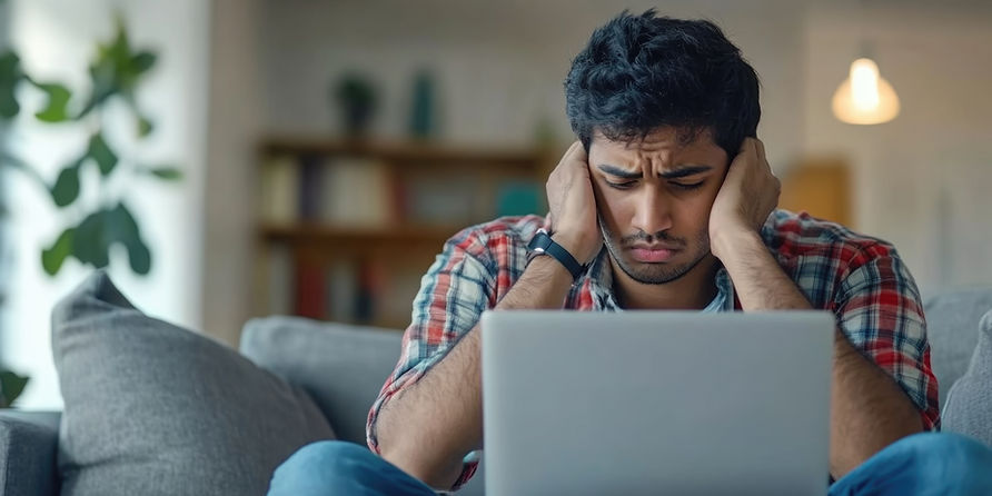 Man holding his head, stressed by laptop