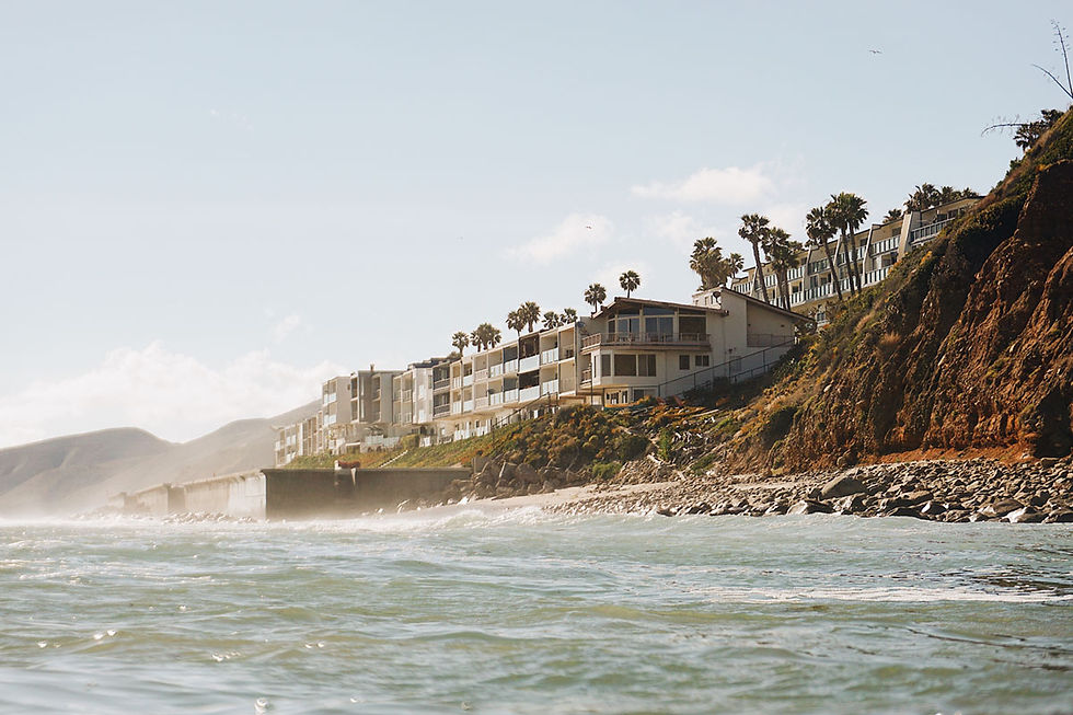 Coastal houses on a cliff overlooking the ocean beach.